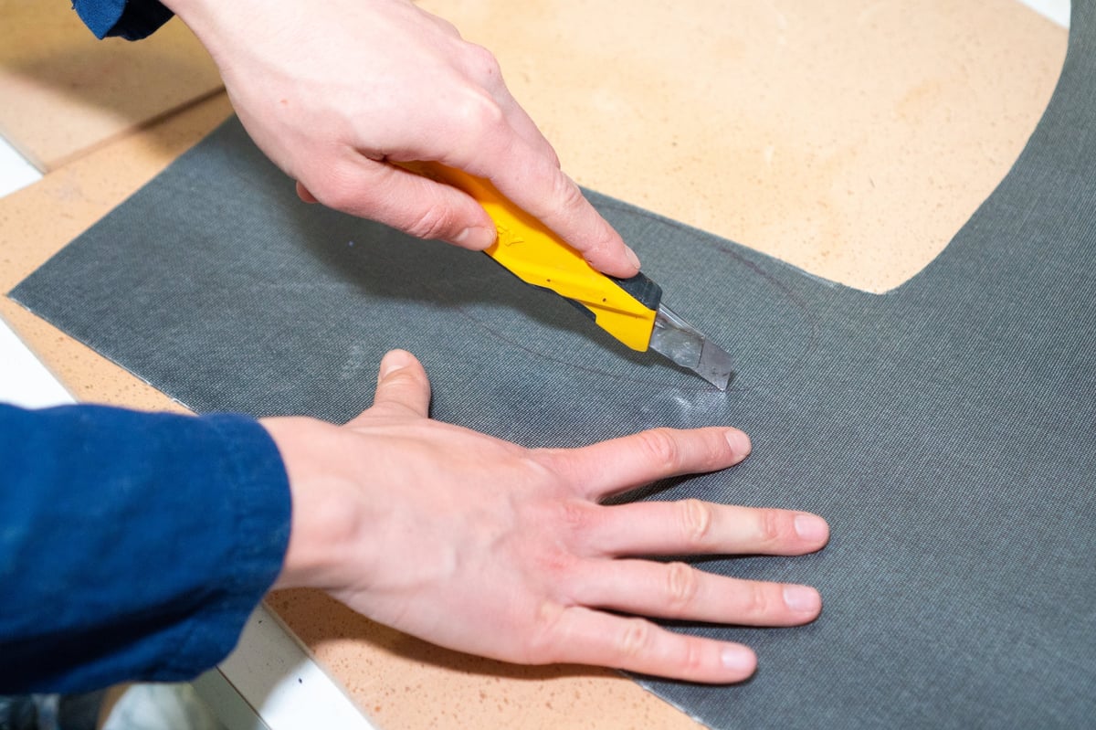 Pedorthist cutting specialist orthotic material during manual fabrication of a custom shoe insole