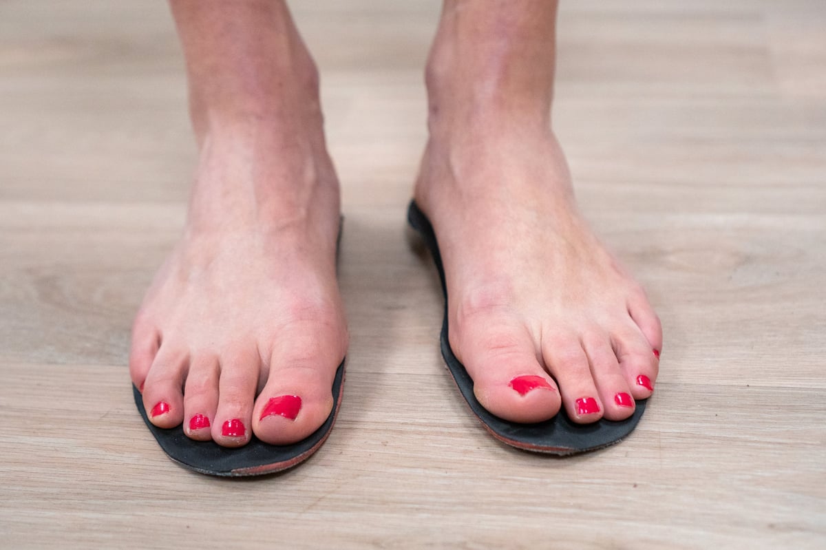 Patient standing while testing custom orthotic insoles inside protective footwear